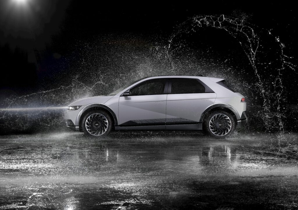 Dynamic black and white shot of a hatchback car with water splashing, ideal for automotive themes.